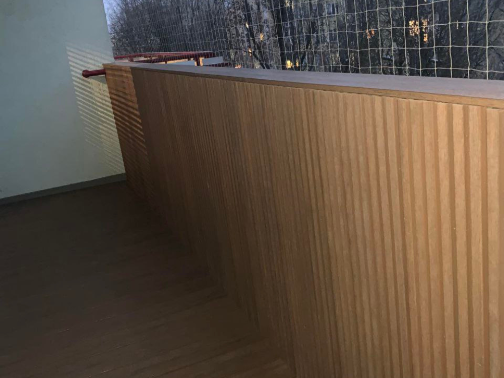 Deska kompozytowa na balkon Advance w kolorze Bear Teak i balustrada obudowana deskami elewacyjnymi typu lamele UltraShield Naturale w kolorze Teak
